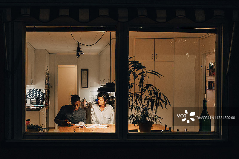 透过窗户看母亲在家辅导儿子学习图片素材