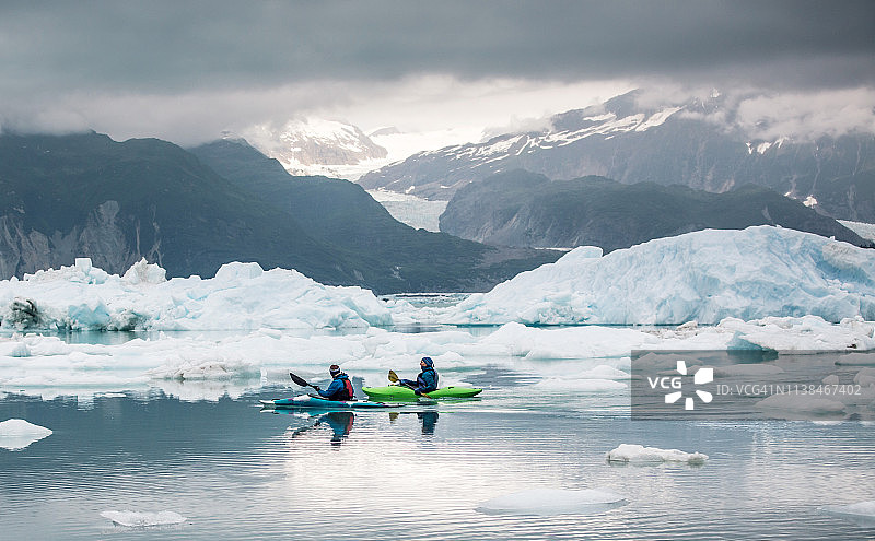 在壮丽天空下冰川泻湖上的两名皮划艇运动员图片素材