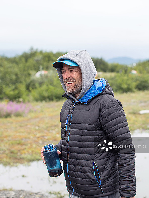 荒野中身穿暖和夹克的微笑男人图片素材