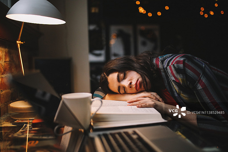 在家工作时，疲惫的年轻女子睡着了图片素材