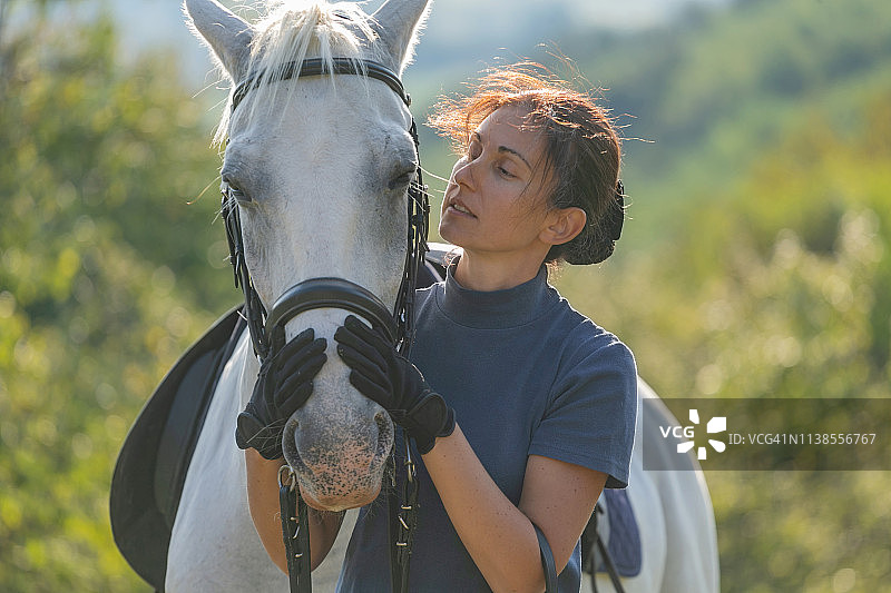 女人充满爱意地抚摸着母马的鼻子图片素材