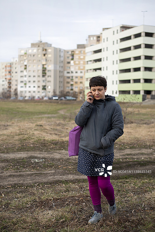 在住宅区与老公寓楼旁打电话的女人图片素材