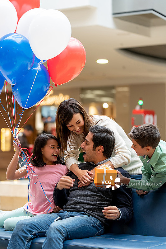 在购物中心给父亲送礼物的快乐家庭图片素材