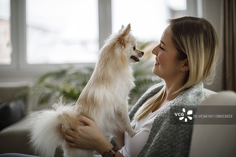 微笑的女人在家抱着可爱的小狗图片素材