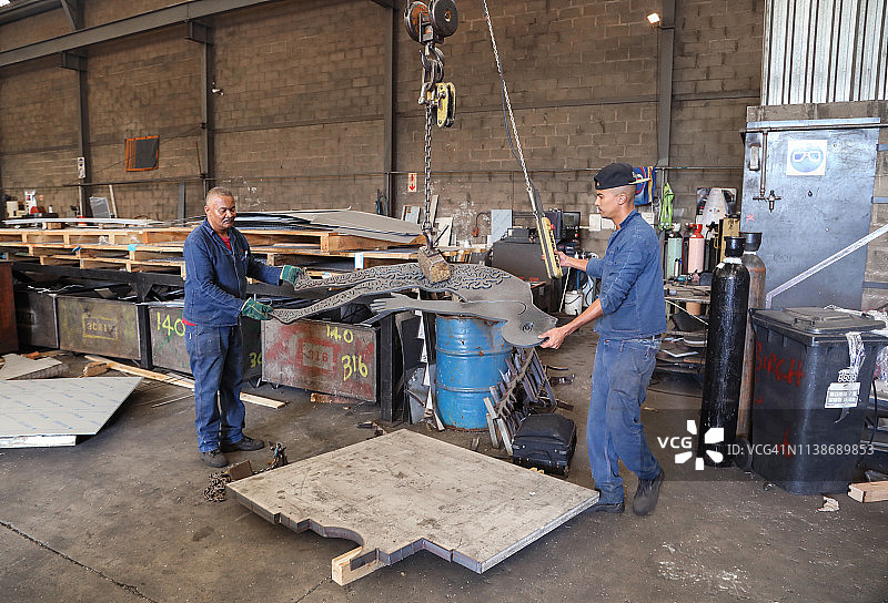 在工厂里搬运重金属的工人们图片素材