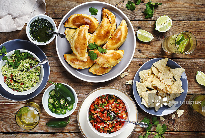 传统墨西哥美食：肉馅卷饼配香菜阿根廷青酱、鳄梨酱、萨尔萨酱、玉米饼和莫吉托图片素材