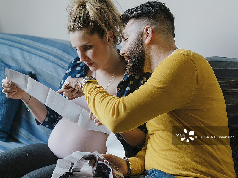 年轻夫妇查看他们宝宝的超声波检查报告图片素材