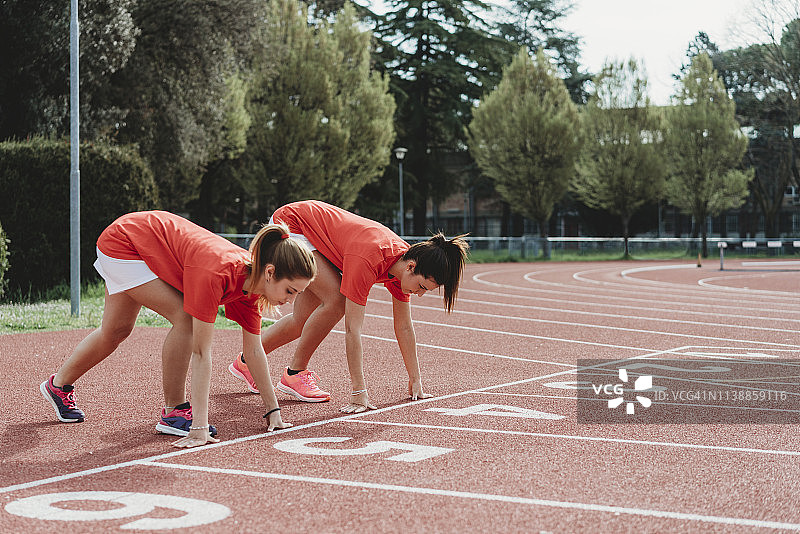 两位女跑步者在起跑线上蹲伏图片素材
