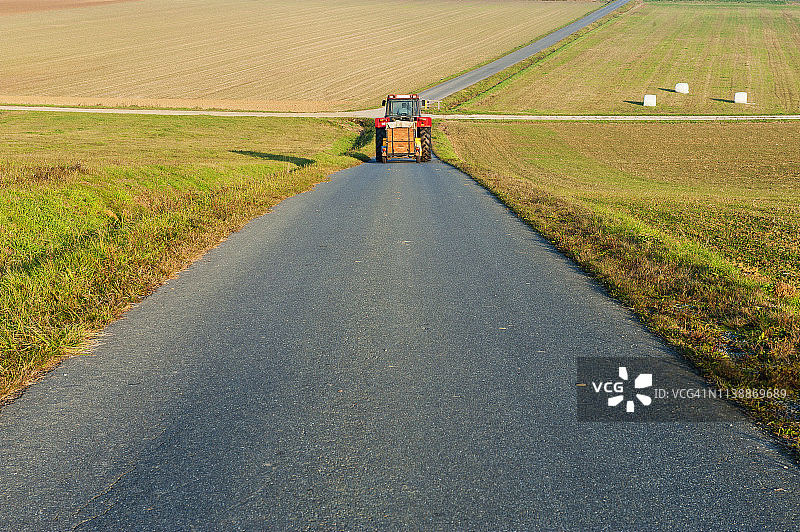 田野旁道路上的拖拉机图片素材