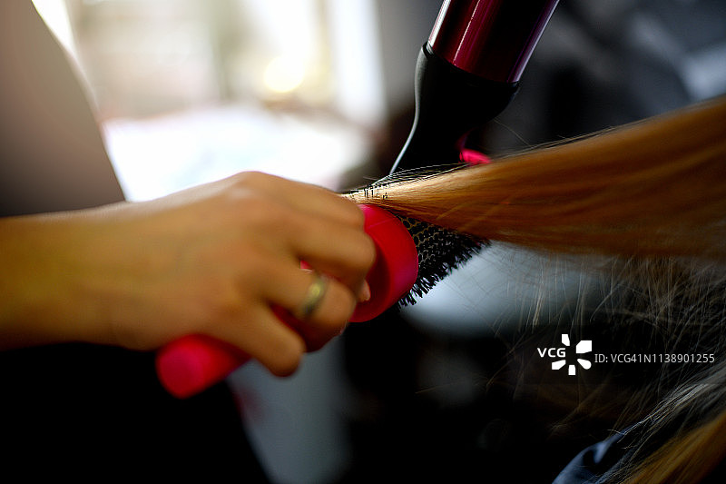 年轻漂亮的女人在美发沙龙吹干头发图片素材