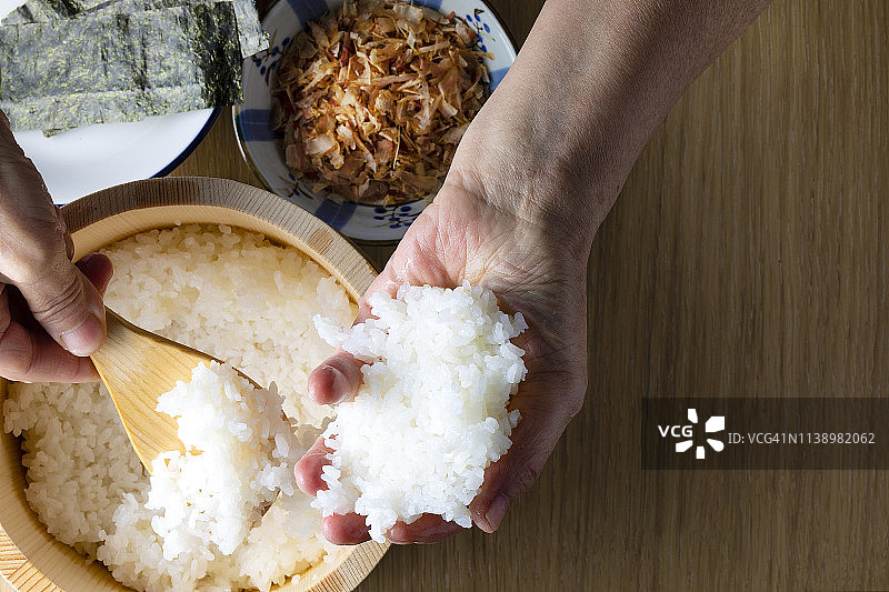 年长的日本女性手持饭团，食材包括干鲣鱼和海苔图片素材