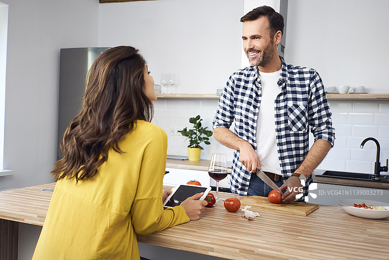 情侣在厨房一起准备意大利面，使用平板电脑图片素材