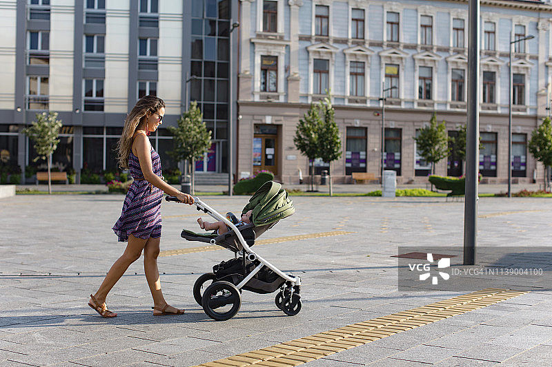母亲在城市中推婴儿车图片素材