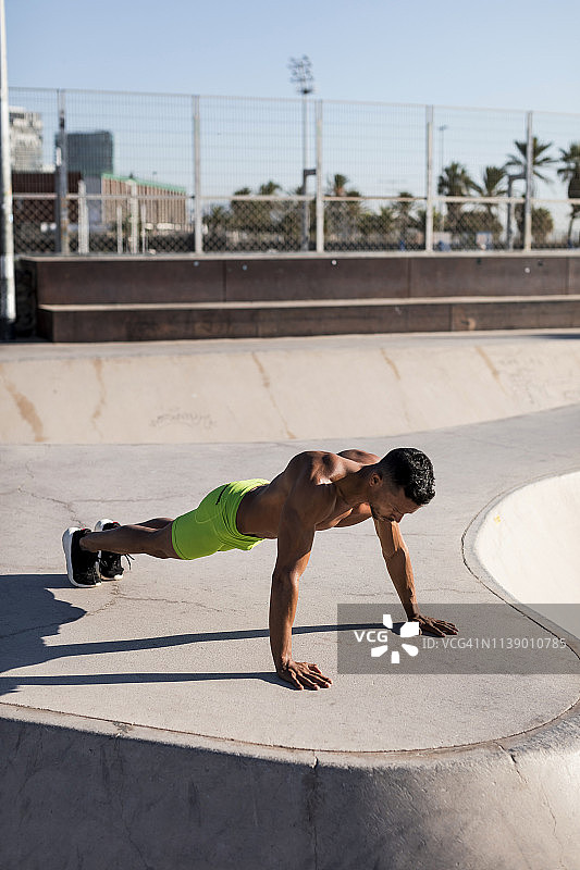 赤膊健壮男人在滑板公园做俯卧撑图片素材