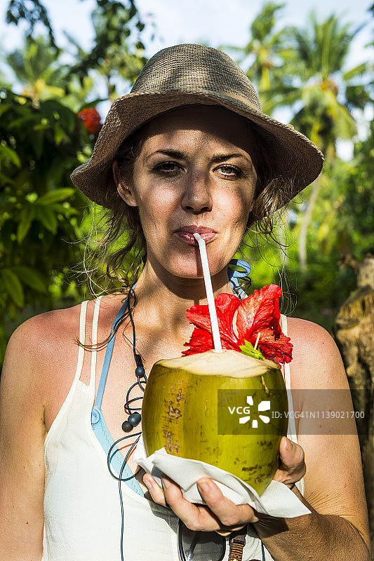 马尔代夫阿里环礁纳拉古来杜岛太阳岛，女人喝新鲜椰子水的肖像图片素材