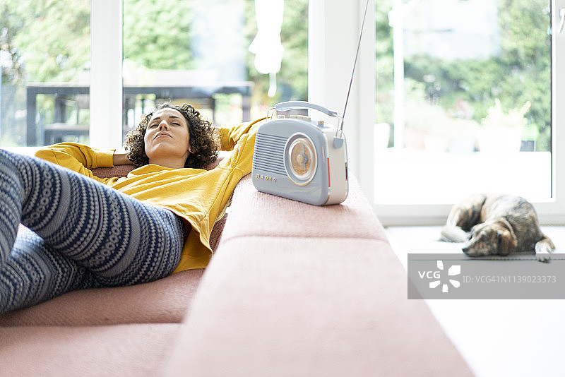 躺在沙发上用便携式收音机听音乐的女人图片素材