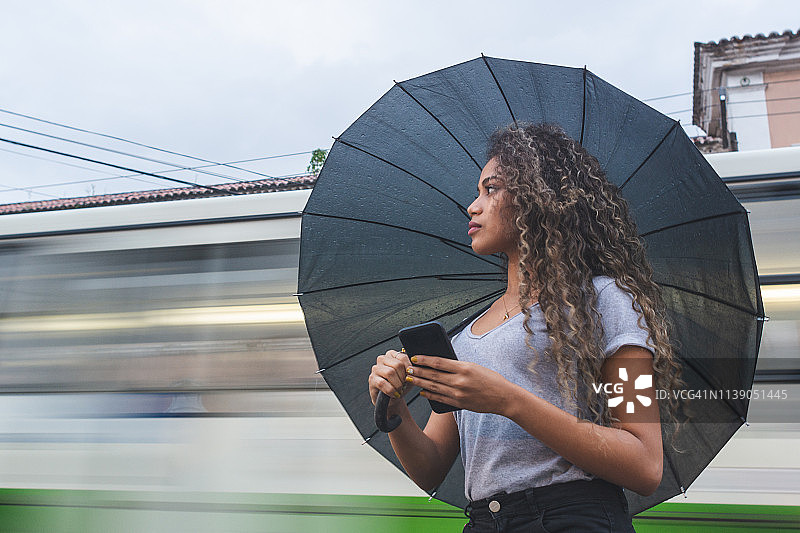 一个年轻女子在雨天等出租车图片素材