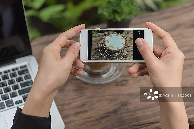 年轻女人用手机拍摄拿铁咖啡图片素材