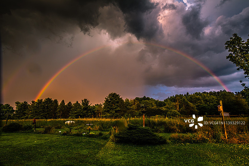 暴风云和绿色牧场上的双彩虹图片素材