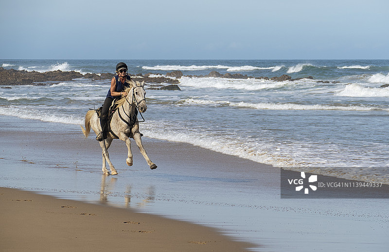 女人在海滩上骑马飞驰图片素材