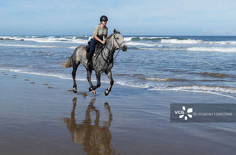 年轻女子在海滩上骑马飞驰图片素材