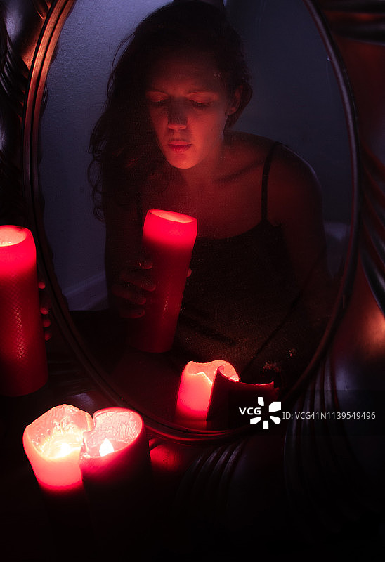 看向镜子旁蜡烛的女人图片素材