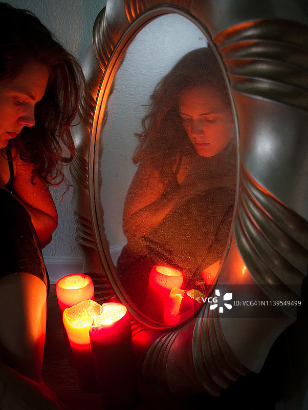 看向镜子旁蜡烛的女人图片素材