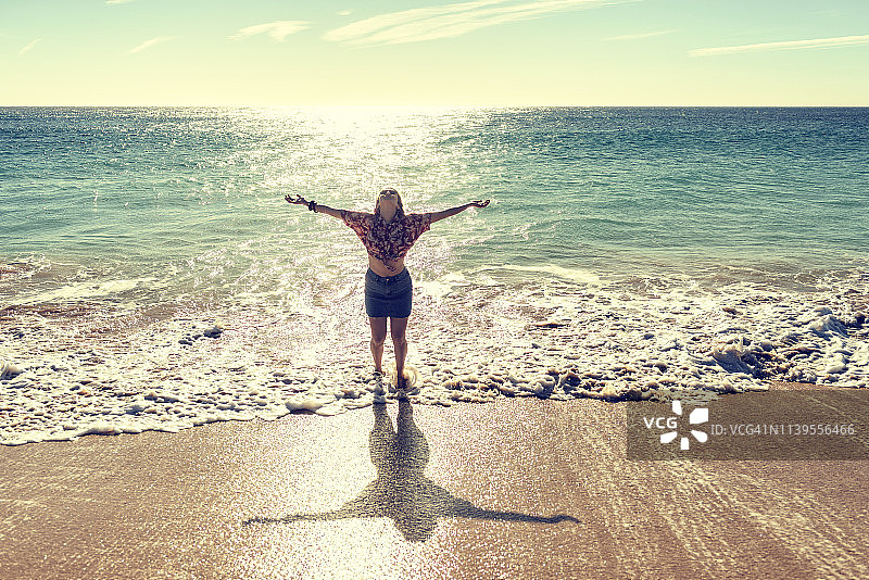 在海滩上举起双臂的女人图片素材