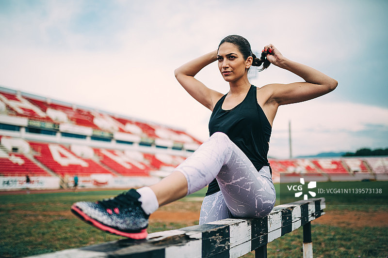 年轻女子在体育场跑道上锻炼图片素材