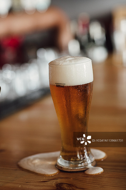 木制柜台上溢出的一品脱啤酒图片素材