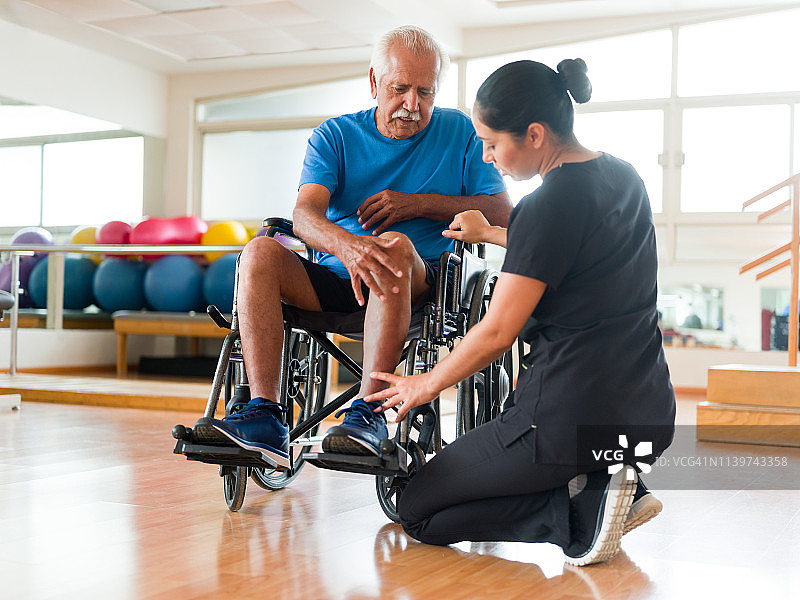 护士检查轮椅上老年男人的腿部图片素材