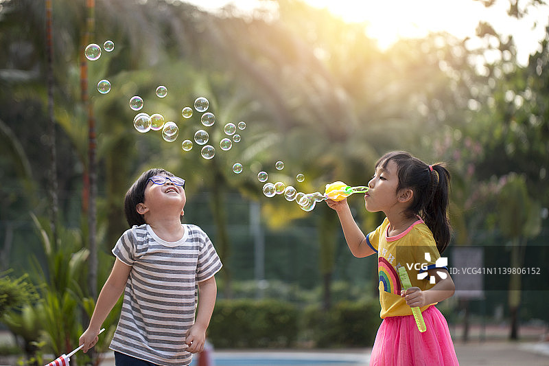 学龄前男孩和女孩玩肥皂泡泡图片素材
