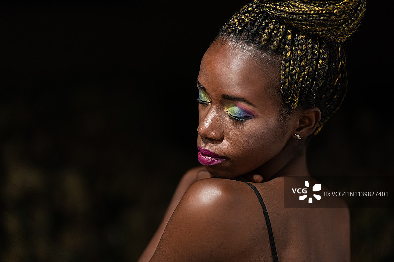 化着彩色妆容向下看的非洲裔女性图片素材