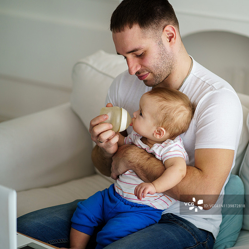 父亲用奶瓶喂儿子图片素材