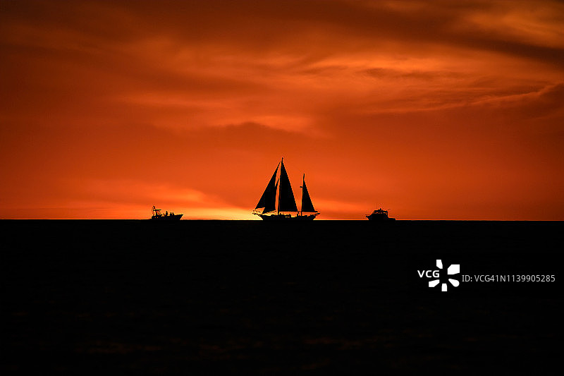 佛罗里达州萨拉索塔附近的长船礁惠特尼海滩日落时分地平线上的三艘船剪影图片素材