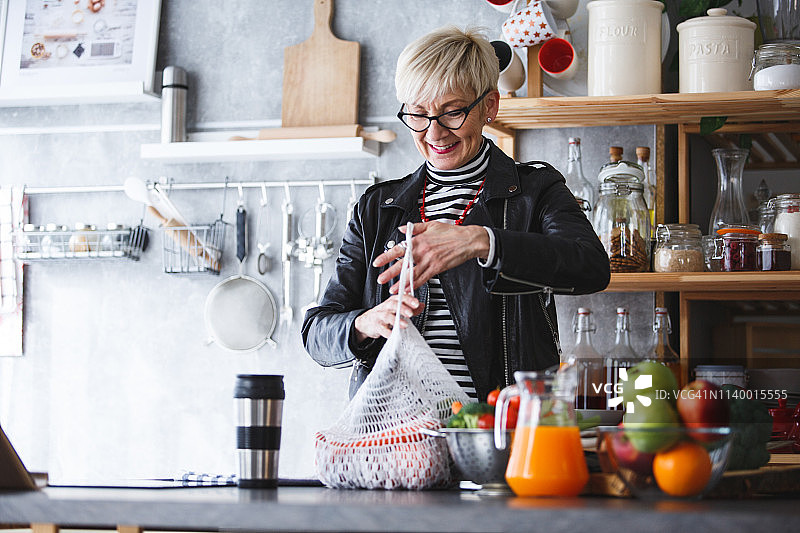 在厨房里从食品店购物回来的女人图片素材