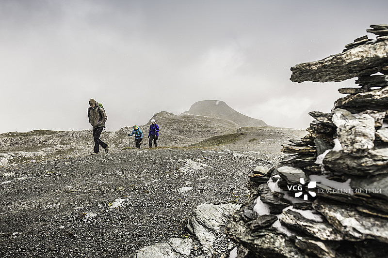 男人和女人徒步旅行者在荒凉的风景中徒步旅行，Fil de Cassons，Segnesboden，格劳宾登州，瑞士图片素材