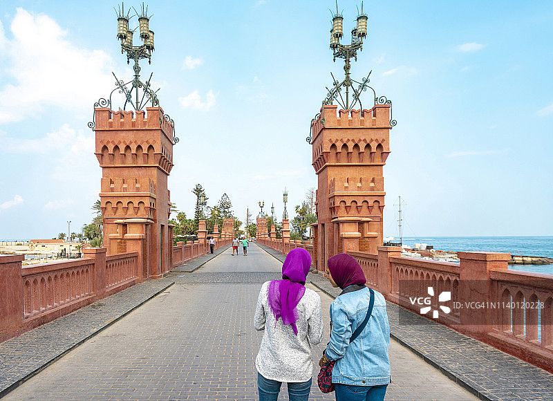 两名女游客在埃及亚历山大港蒙塔扎宫桥上拍照图片素材