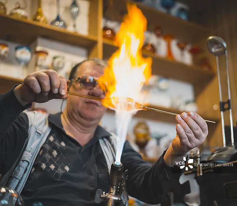 玻璃吹制者正在塑形熔融玻璃图片素材