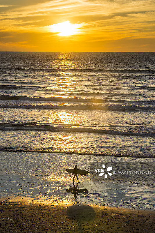 美国加州日落时分海滩上的女性冲浪者图片素材
