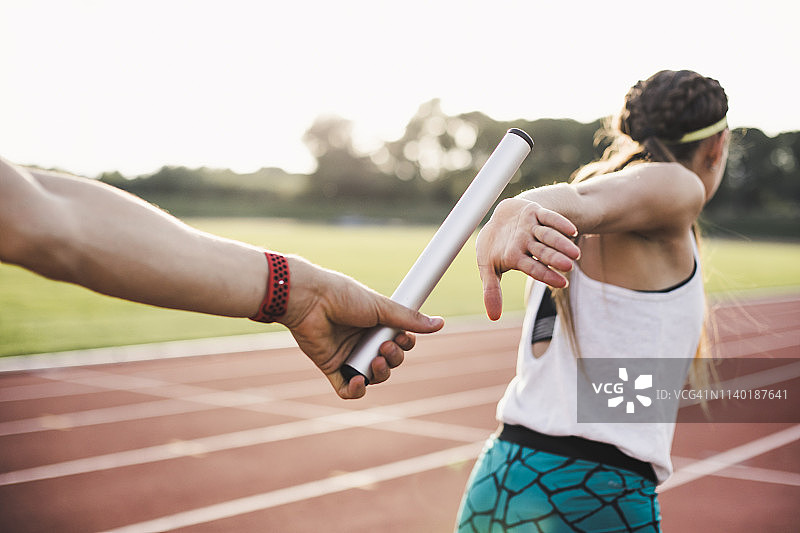 运动员将接力棒传递给女运动员的特写图片素材