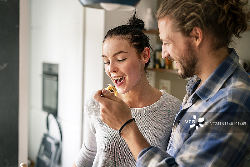 年轻情侣一起准备食物，品尝意大利面图片素材