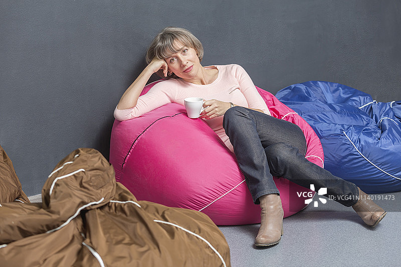 女人 портрет 在办公室的豆袋上放松地喝着咖啡图片素材