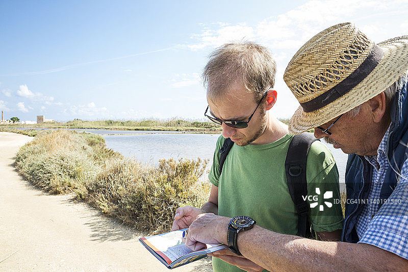 意大利西西里岛 Vendicari 自然保护区，年长的父亲和成年的儿子在看地图图片素材