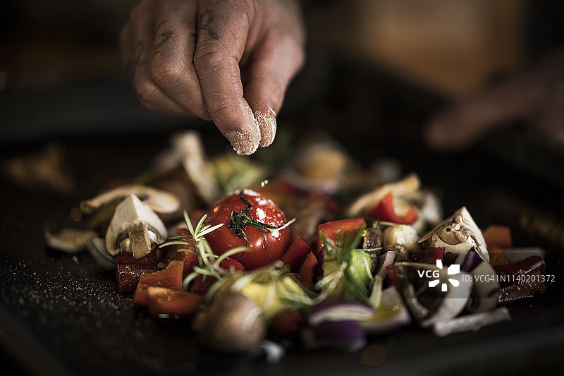 手在烤盘上给蔬菜调味图片素材