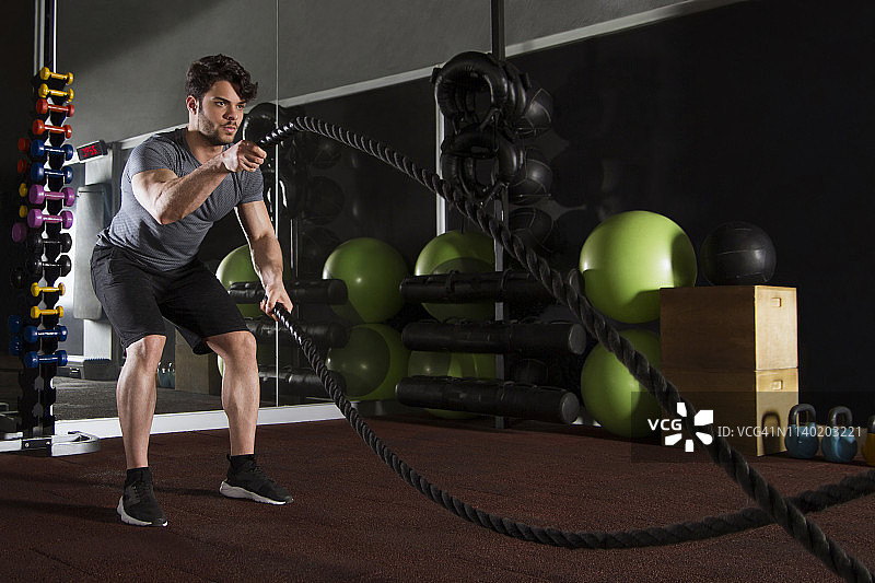 年轻运动员在健身房用战绳锻炼图片素材