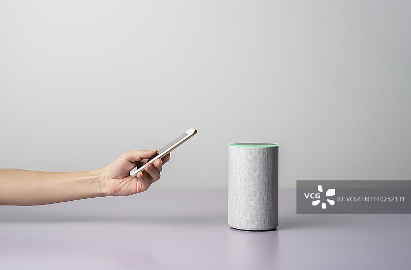 女人使用带智能手机的智能音箱图片素材