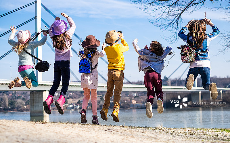 在河岸边跳跃的儿童群体的背影图片素材
