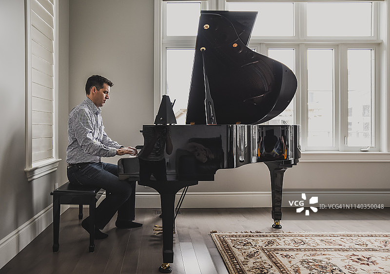 在明亮房间里演奏小型三角钢琴的男人图片素材