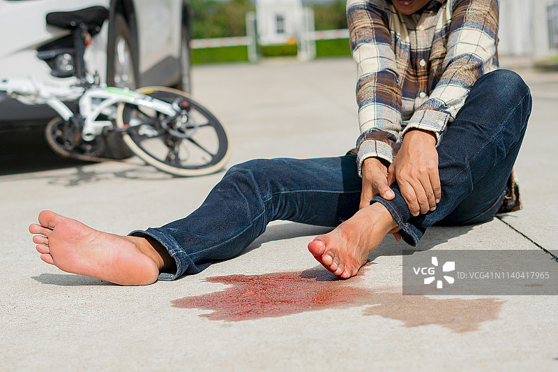 男子骑自行车摔倒后在路上发生事故，腿部受伤图片素材